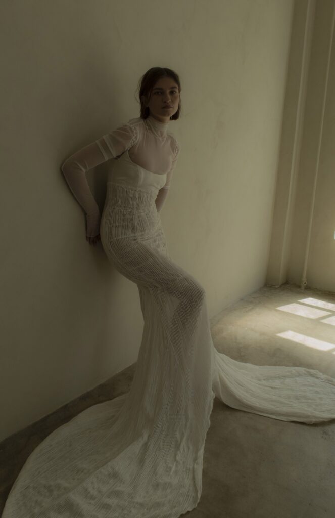 Cinq's wedding dress designs give a vintage feeling while being modern and timeless. This piece is a sheer long sleeve wedding gown.